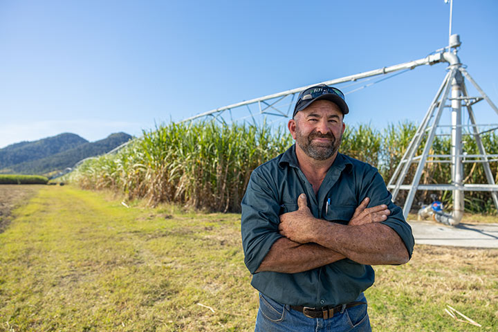 Canegrower, Andrew Vassallo standing in front of his sugarcane crop and new centre pivot irrigator