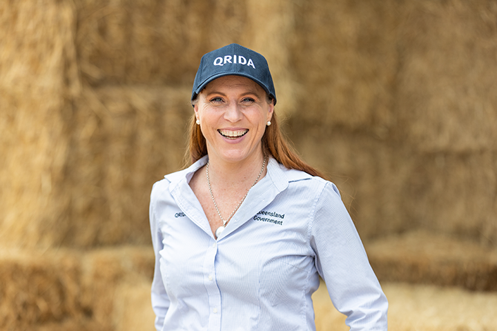 Manager for Disasters and Drought, Sheree Finney stand smiling at teh camera wearing a blue and white striped shirt and navy blue cap with QRIDA written in white letters across it.
