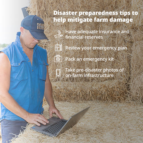 A man works on his laptop on a stack of haybales
