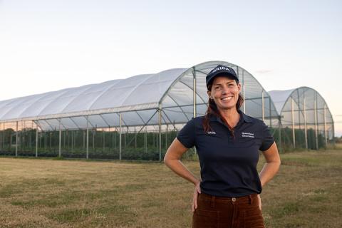 Regional Area Manager, Tegan McBride standing in front of greenhouse