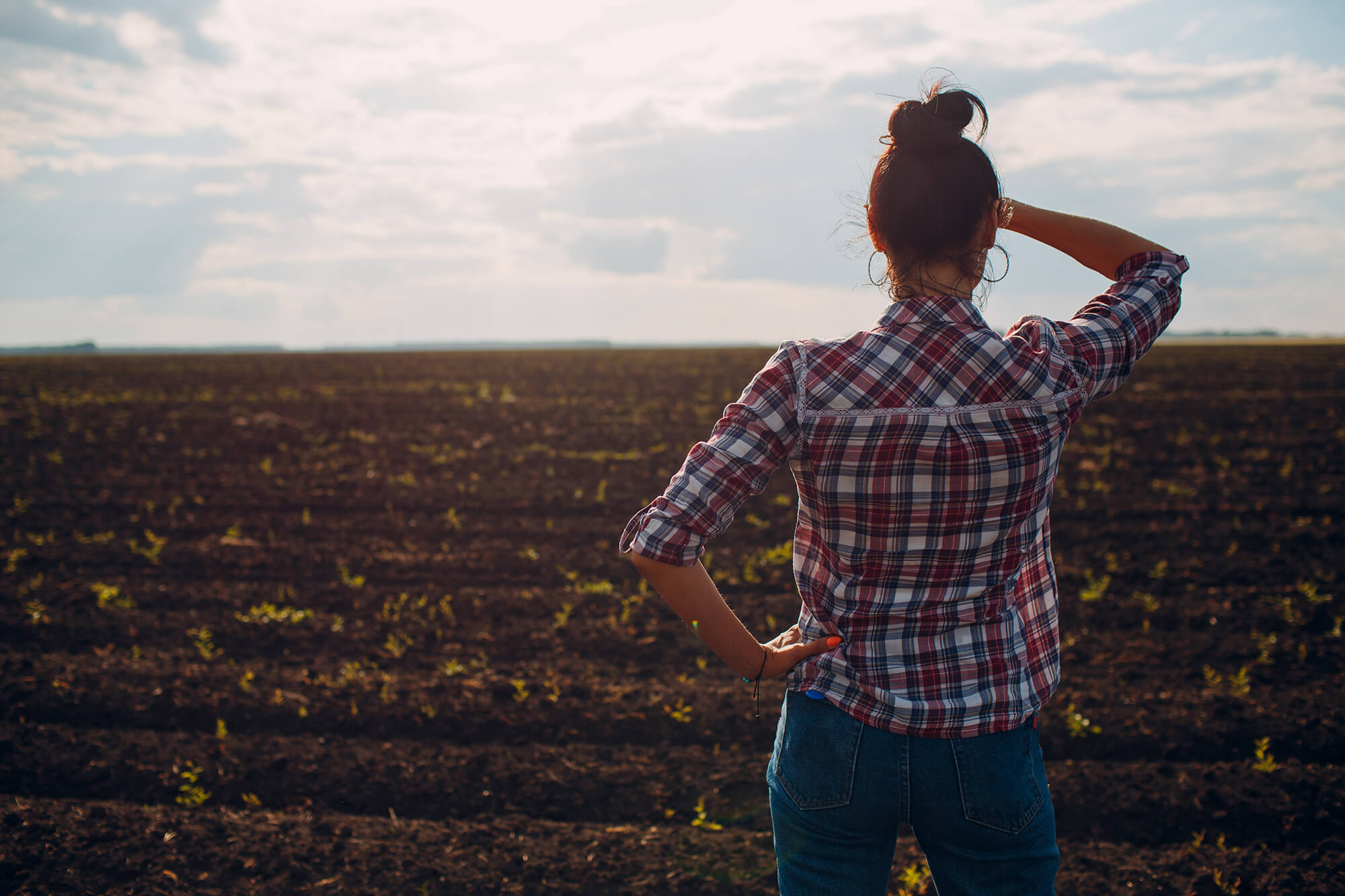 Female farmer looking into distance of dry field